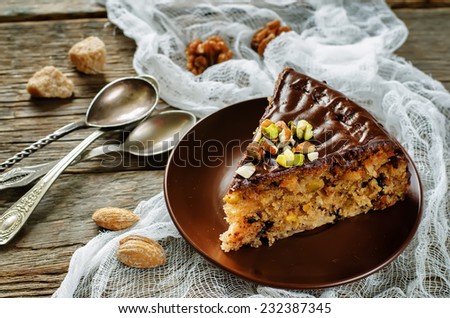 cake with nuts, chocolate chips and chocolate glaze on dark wood background. tinting. selective focus
