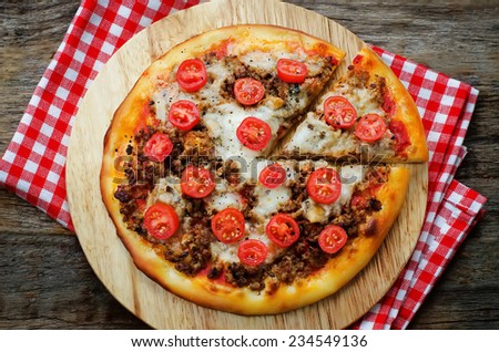 pizza with meat, mozzarella and tomatoes on a dark background. tinting. selective focus