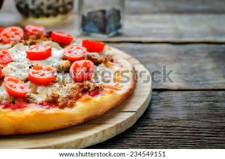 pizza with meat, mozzarella and tomatoes on a dark wood background. tinting. selective focus