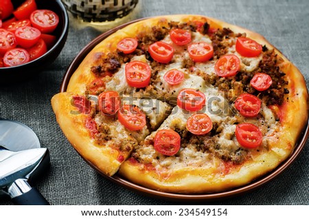 pizza with meat, mozzarella and tomatoes on a dark background. tinting. selective focus
