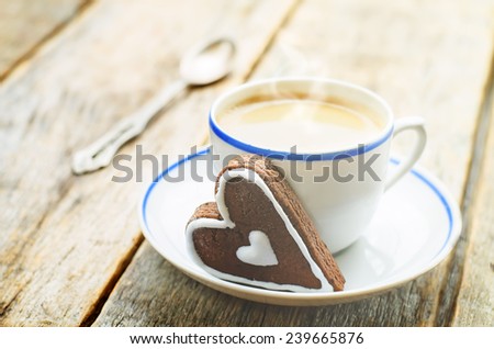 cup of coffee with the chocolate cookies in the shape of a heart on a dark wood background. tinting. selective focus