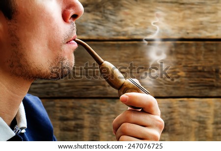 man smoking a pipe about wood walls. tinting. selective focus