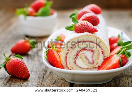 cake roll with strawberries and cream cheese on a dark wood background. tinting. selective focus
