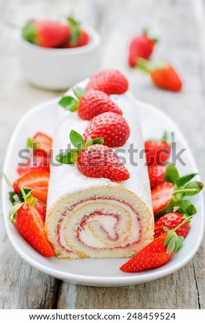 cake roll with strawberries and cream cheese on a white wood background. tinting. selective focus
