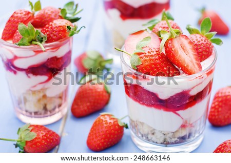layered dessert with strawberries, biscuit cake and cream cheese on a blue wood background. tinting. selective focus