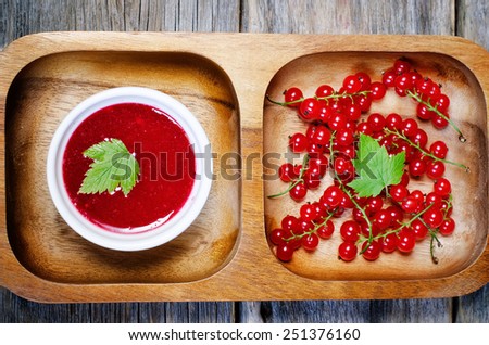 red currants jam in the bowl on a dark wood background. toning. selective focus