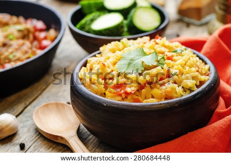 saffron rice with vegetables and cilantro on a dark wood background. the toning. selective focus