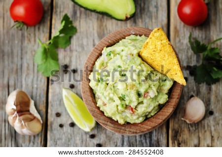 guacamole with corn chips on a dark wood background. the toning. selective focus
