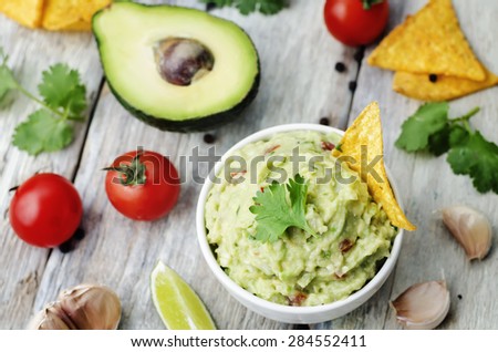 guacamole with corn chips on a white wood background. the toning. selective focus