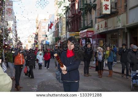 NEW YORK, NEW YORK - FEBRUARY 17: Young Asian woman tries out a Chinese firecracker during Chinese New Year Parade.  Taken February 17, 2013 in  NYC.