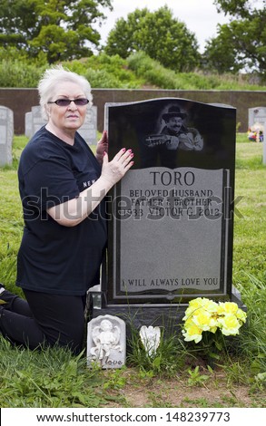 QUEENS, NEW YORK - JUNE 6: Sister of famed cuatro player Yomo Toro visits his grave on anniversary of his death.   Taken June 6, 2013 at Saint Michael's Cemetery in New York.