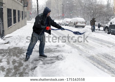 BRONX, NEW YORK - JANUARY 21: man shoveling during  a 6 to 10 inch snow storm and teen temperatures along Ogden avenue and 162nd street.  Taken January  21,  2014 in the Bronx,  New York.