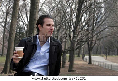 Man sits in park as he drinks his beverage.  Photographed in Central Park in NYC on a cool day in March, 2008.