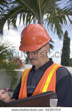 Man takes notes while overlooking backyard construction.   He was in his seventies and was photographed in Bayamon, Puerto Rico in December, 2009.