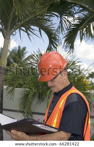 A senior looks at notes during the construction of a backyard.  Photographed in Bayamon Puerto Rico in December, 2009.  He was in his seventies at the time and of Puerto Rican ethnicity.