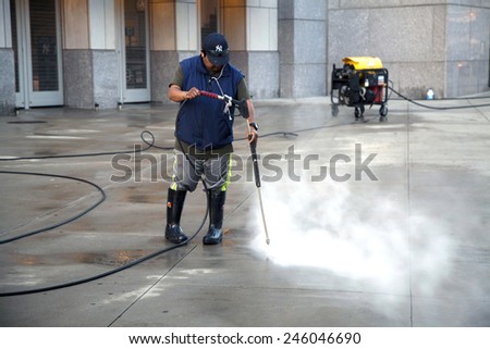 BRONX, NEW YORK - MAY 29: Man uses pressure washer to clean Yankee Stadium sidewalk.   Taken May 29, 2014 in the County of the Bronx, NY.