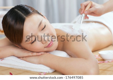 A young lady enjoy body mask in spa salon