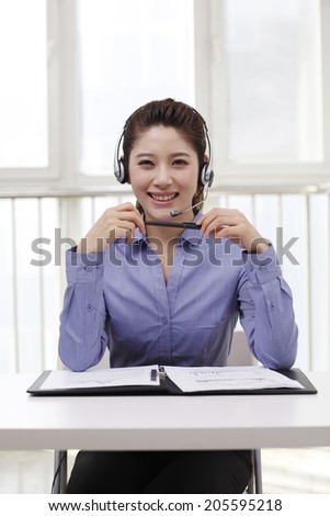Businesswoman with headset writing on portfolio