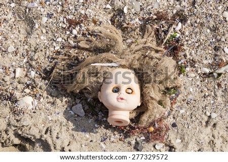 Head of children\'s doll thrown by the sea  on the beach trash