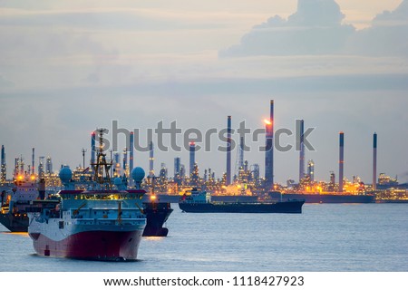 Seismic survey vessel and cargo container ships off the coast of Singapore Island Petroleum Chemical Refinery Plants