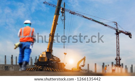 construction workers engineer working in construction site under view of crane excavator in sun set background