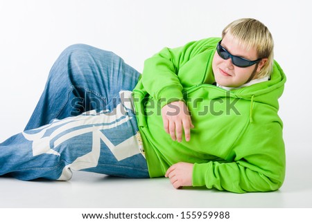 Fat young man in a green fleece and black glasses lying on the floor