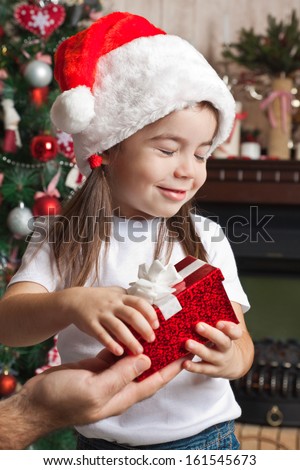 Dreaming girl with  closed eyes in Santa hat opens the Christmas gift