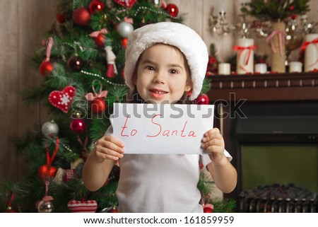 Little girl with letter to Santa near christmas tree