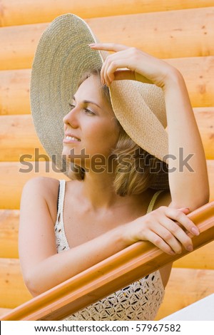Young woman in a hat standing near the house and dreaming