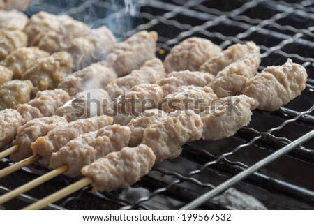 Grilled Toast meat ball on steel skewer in a smoke