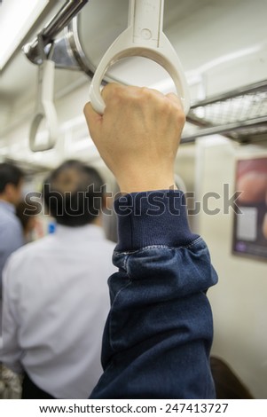 Hand of passengers hold on rail handle of transit system, train