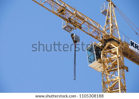 Construction crane tower on blue sky background. Crane and building working progress. Yellow lifting faucet. Empty Space for text. Construction concept. Site. New buildings with a crane. Tower crane