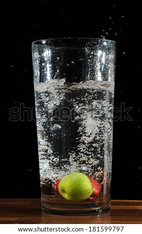 A fast shutter of a fruits in a jar full of plain water in isolated black background