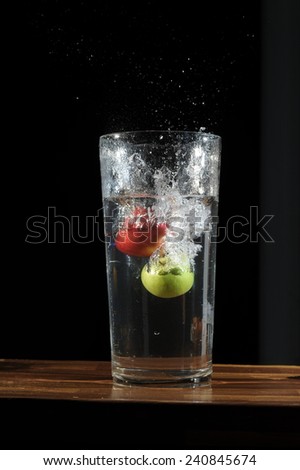 A fast shutter of a fruits in a jar full of plain water in isolated black background