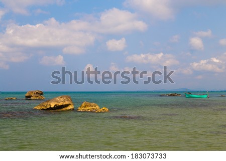 large stones with seashells in clean sea water and a boat