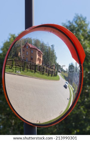 reflection in the mirror of the road from a stone blocks at the house, lawn and woods