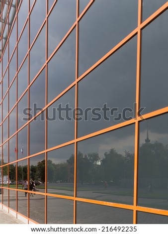a reflection of the city and a high glass wall of an office building with orange stripes