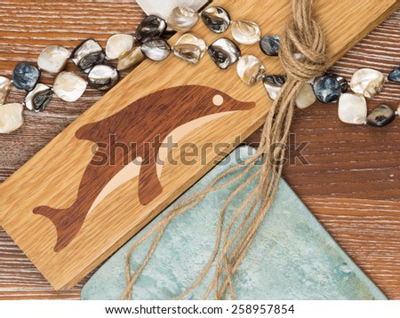 marine theme in interior design with wooden flooring with inlaid dolphin, aged ceramic tiles, mother of pearl beads, salted wood and rough twine