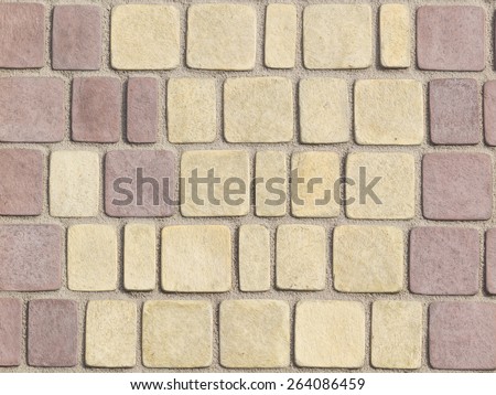 textured paving tiles imitating stone path with rounded edges and seams are covered with fine beige marble chips