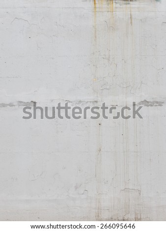 Old painted white wall with rusty streaks and peeling paint