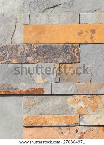Wall from natural brown, ocher and gray stone laid as a brick