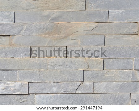 wall of rough natural marble gray stone with the cleaved surface, laid horizontally, like a brick