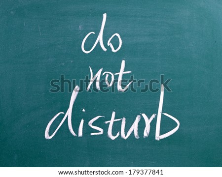 Do Not Disturb written by hand in white chalk on a used blackboard