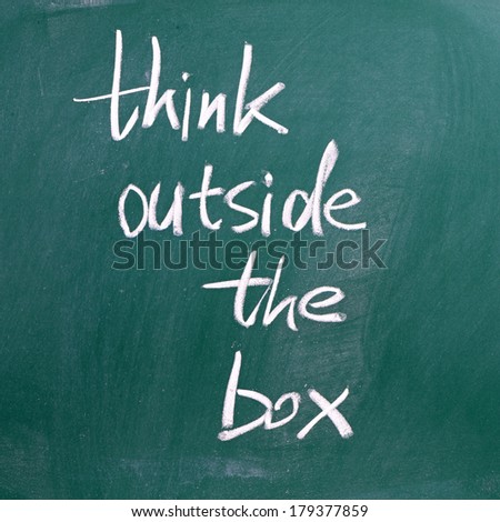 The phrase Think Outside the Box written in white chalk on a blackboard