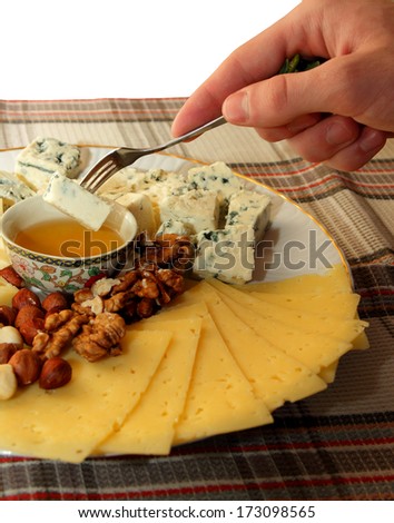 The guy holding the fork in hand with a piece of cheese to dip it in honey