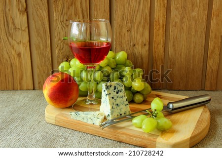 Still-life with a glass of rose wine, cheese and fruit