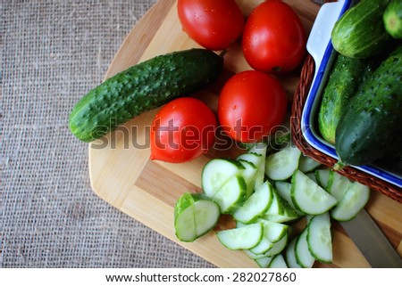 Cucumbers and tomatoes lying on the board and chopped salad.