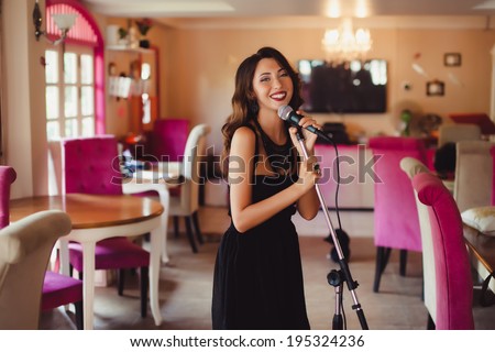 young beautiful girl sings into a microphone in the room