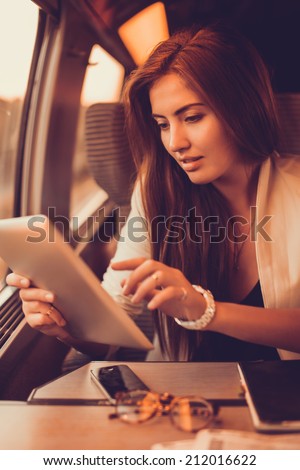 young girl works on the tablet on the internet and goes to the train
