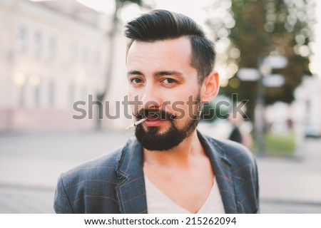 young man smokes a cigarette on the street